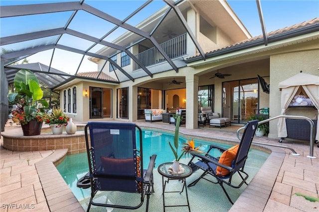 pool featuring glass enclosure, ceiling fan, a patio area, and outdoor lounge area