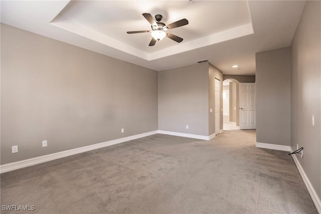 carpeted spare room featuring a raised ceiling and ceiling fan