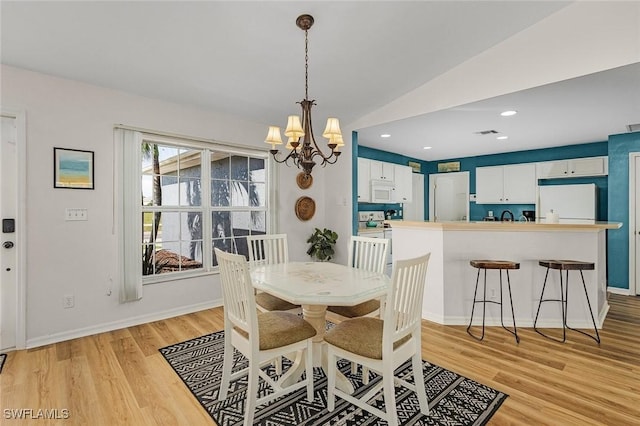 dining space featuring a chandelier, light hardwood / wood-style flooring, and lofted ceiling