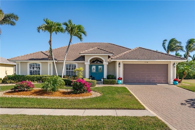 mediterranean / spanish-style house featuring a front yard and a garage