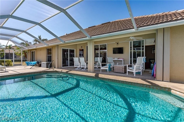 view of pool featuring glass enclosure, ceiling fan, and a patio