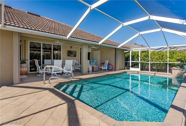 view of swimming pool with glass enclosure, ceiling fan, and a patio