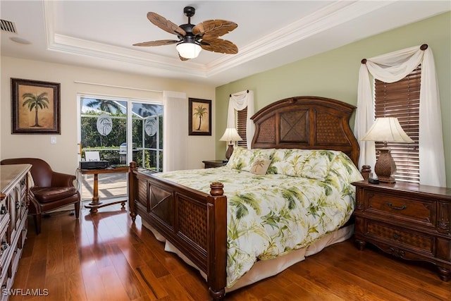 bedroom featuring access to exterior, a tray ceiling, dark hardwood / wood-style floors, and ceiling fan