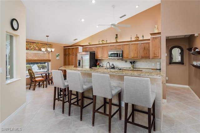 kitchen featuring backsplash, high vaulted ceiling, a spacious island, light stone counters, and stainless steel appliances