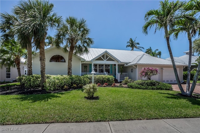 ranch-style home with a front yard, covered porch, metal roof, and an attached garage