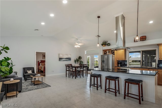 kitchen featuring a breakfast bar area, decorative backsplash, hanging light fixtures, island exhaust hood, and stainless steel fridge with ice dispenser