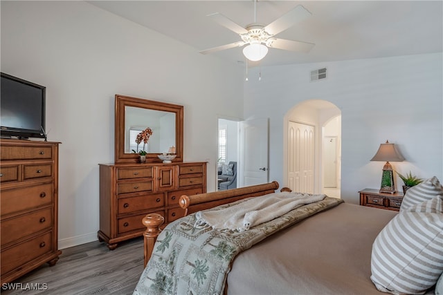 bedroom with visible vents, arched walkways, wood finished floors, vaulted ceiling, and a closet