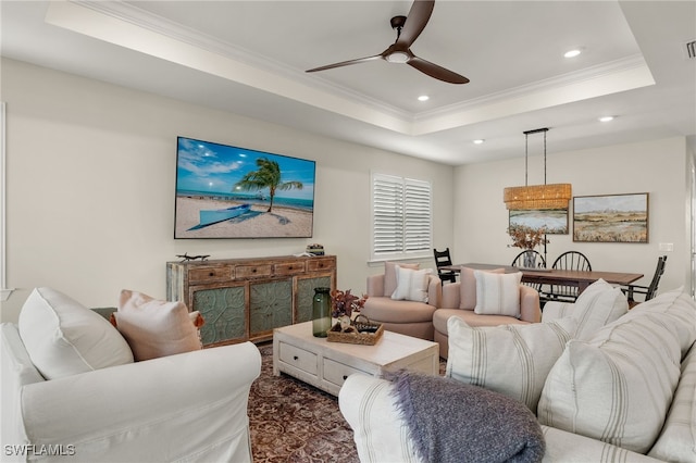 living room with a tray ceiling, crown molding, and ceiling fan