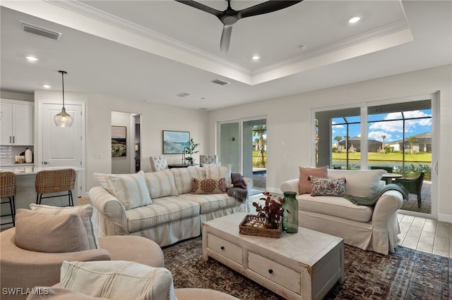 living room with a raised ceiling, crown molding, ceiling fan, and dark wood-type flooring