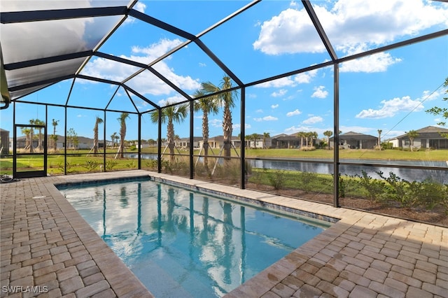 view of pool featuring glass enclosure, a water view, and a patio