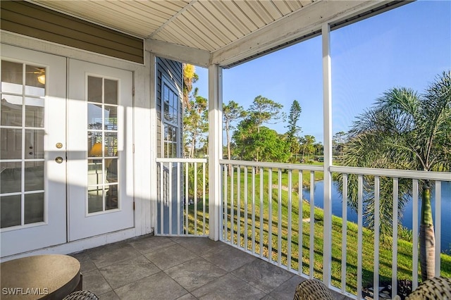 unfurnished sunroom featuring a water view, wooden ceiling, and french doors