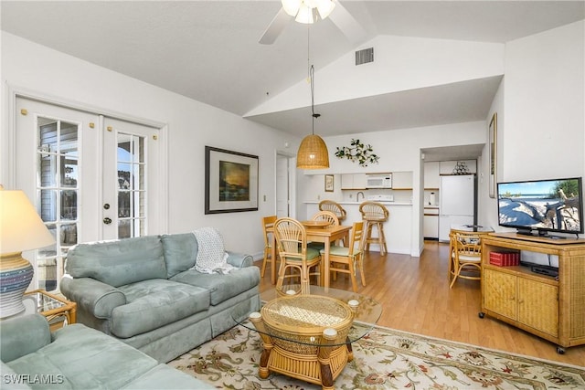 living room featuring ceiling fan, lofted ceiling, light hardwood / wood-style flooring, and french doors