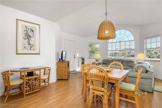 dining space with light hardwood / wood-style floors and vaulted ceiling