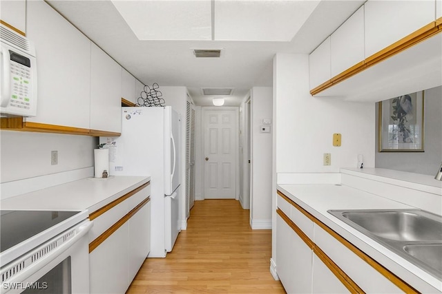 kitchen featuring white cabinetry, light wood-type flooring, white appliances, and sink