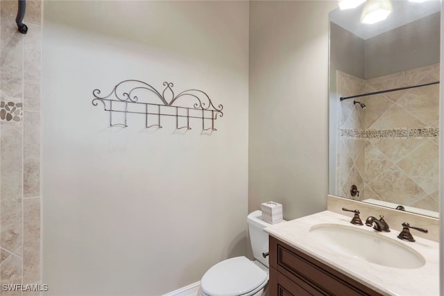 bathroom with toilet, vanity, and tiled shower