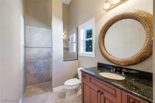 bathroom with tile patterned flooring, vanity, a tile shower, and toilet