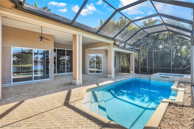 view of swimming pool featuring an in ground hot tub, ceiling fan, glass enclosure, and a patio