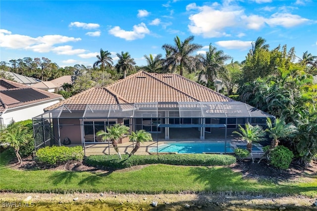 rear view of property with a lanai and a lawn