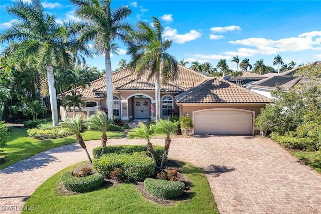 mediterranean / spanish-style home featuring a garage and a front yard