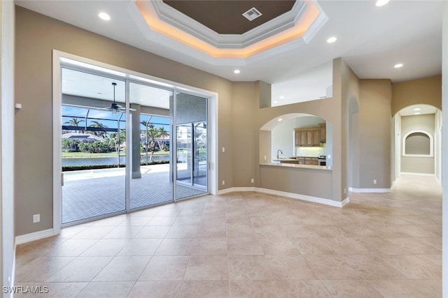 unfurnished room featuring ornamental molding, ceiling fan, light tile patterned floors, and a tray ceiling