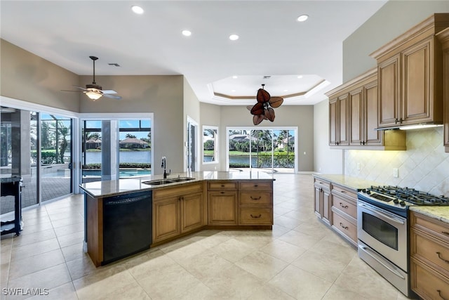 kitchen with black dishwasher, a water view, sink, stainless steel gas range oven, and a raised ceiling