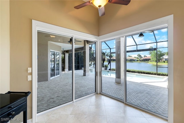 doorway to outside featuring a water view, light tile patterned floors, and ceiling fan