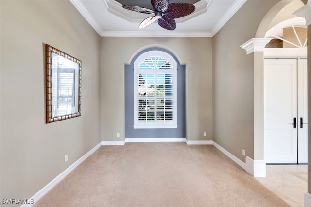 carpeted empty room featuring a tray ceiling, ornamental molding, and ceiling fan