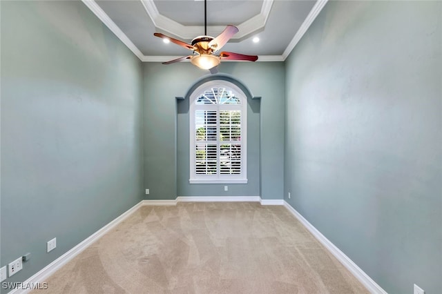 carpeted empty room with a raised ceiling, ceiling fan, and crown molding