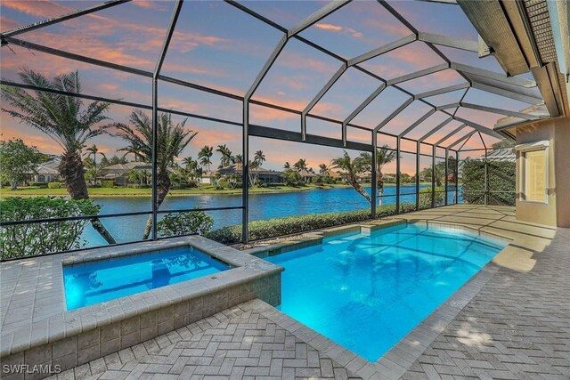 pool at dusk featuring an in ground hot tub, a water view, a patio area, and a lanai