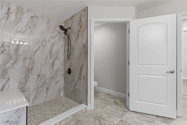 bathroom with a tile shower and toilet