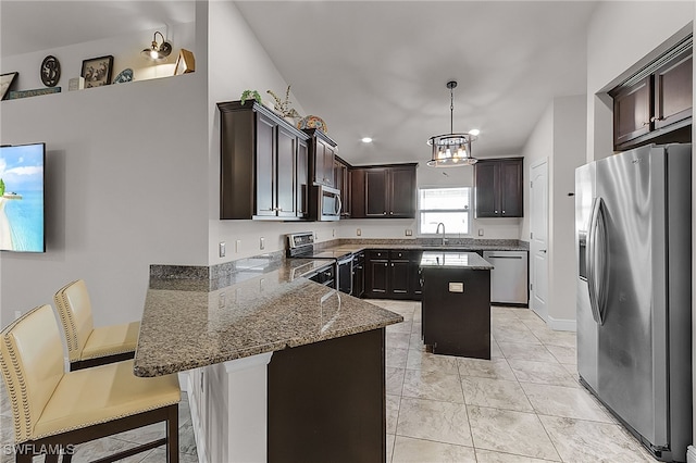 kitchen featuring hanging light fixtures, a kitchen breakfast bar, dark stone countertops, a kitchen island, and appliances with stainless steel finishes