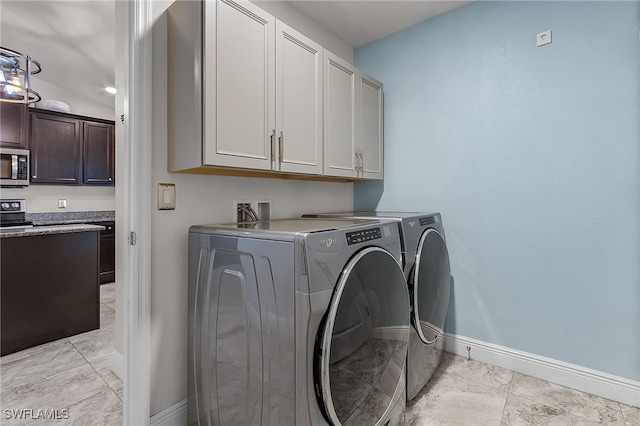 clothes washing area with cabinets and washer and clothes dryer