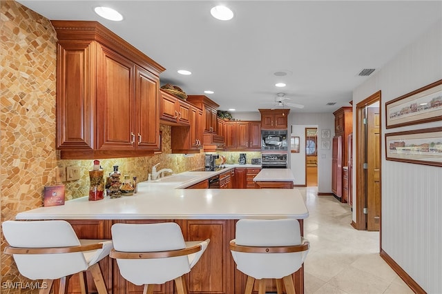 kitchen with sink, kitchen peninsula, a kitchen bar, decorative backsplash, and black appliances