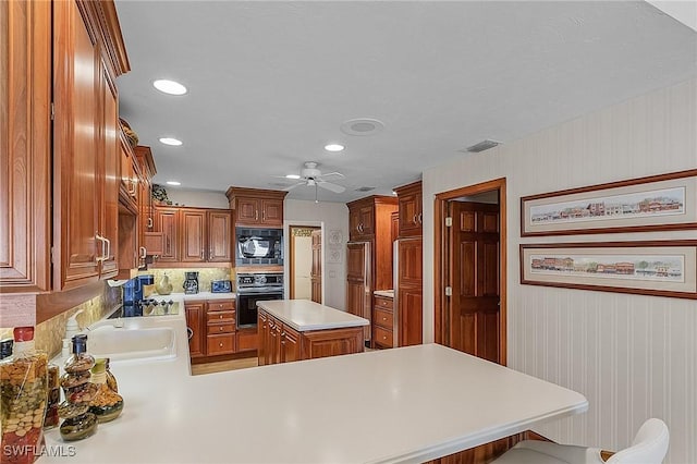 kitchen with tasteful backsplash, a kitchen breakfast bar, kitchen peninsula, a kitchen island, and black appliances