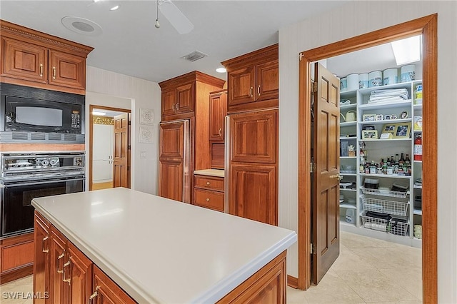 kitchen with ceiling fan, a center island, light tile patterned flooring, and black appliances