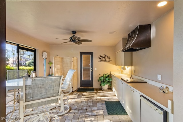 interior space featuring white cabinets, sink, ceiling fan, range hood, and stovetop