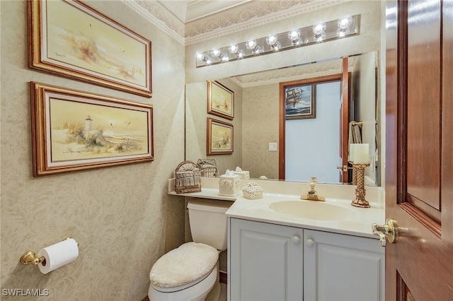 bathroom with toilet, vanity, and ornamental molding