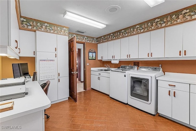 laundry area featuring light hardwood / wood-style floors, washing machine and dryer, and sink