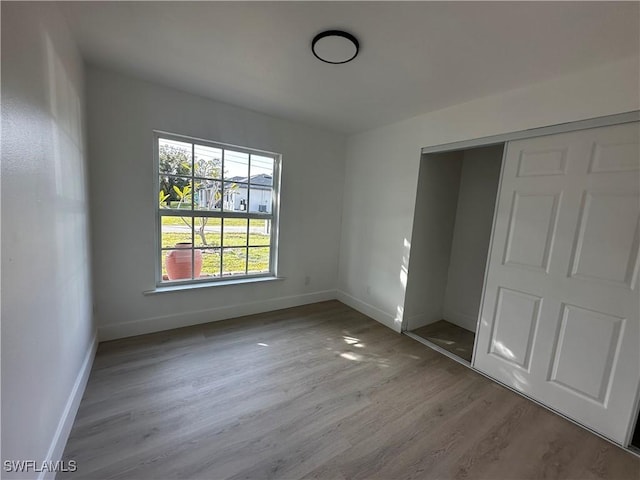 unfurnished bedroom with light hardwood / wood-style flooring and a closet