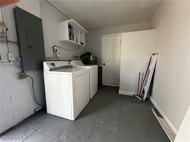 clothes washing area with dark tile patterned floors, electric panel, and washing machine and clothes dryer