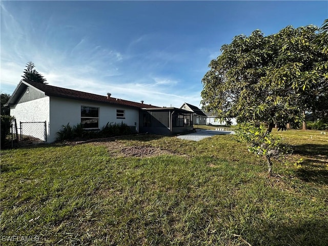 back of property featuring a sunroom and a lawn