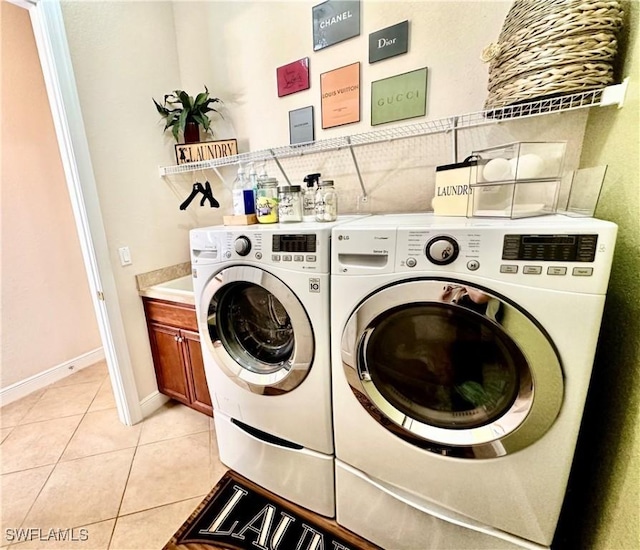 laundry area featuring washing machine and clothes dryer, light tile patterned flooring, and cabinets