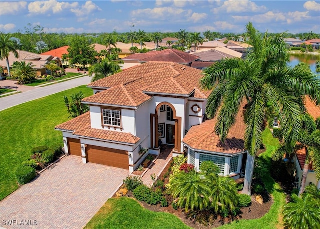 mediterranean / spanish-style house with a garage and a front lawn