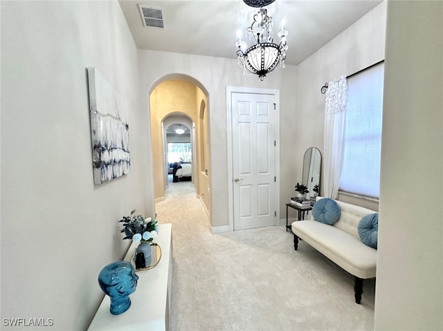 hallway featuring a chandelier and light colored carpet