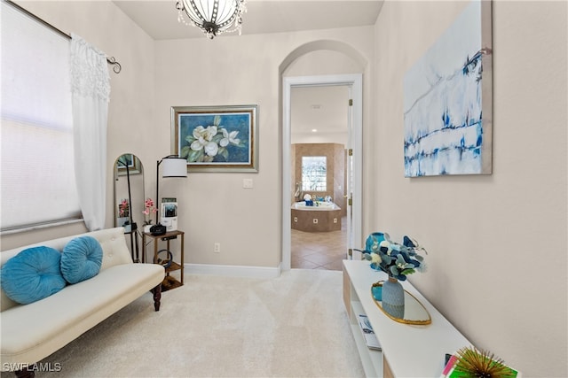 living area featuring light colored carpet, a healthy amount of sunlight, and a notable chandelier