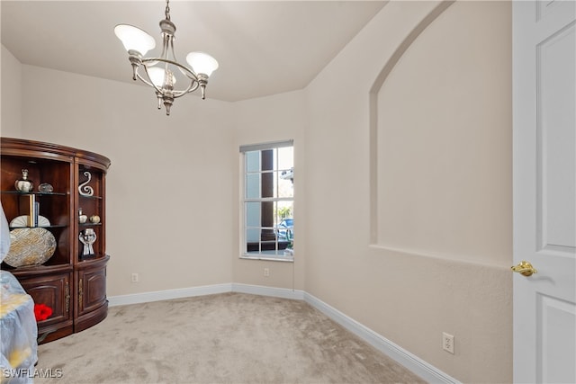 carpeted spare room with a chandelier