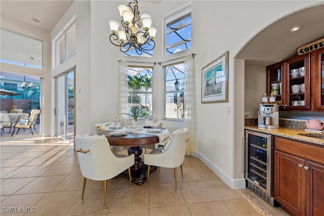 tiled dining area with wine cooler, a towering ceiling, indoor bar, and an inviting chandelier