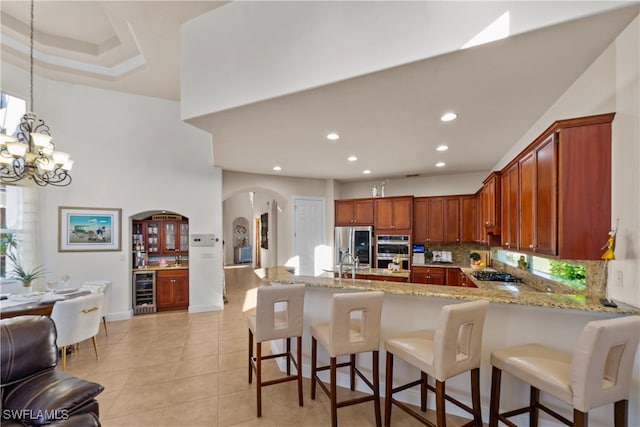 kitchen featuring decorative backsplash, stainless steel appliances, beverage cooler, decorative light fixtures, and a chandelier