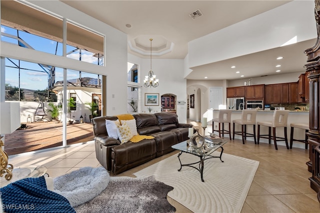 living room featuring a notable chandelier, a towering ceiling, and light tile patterned floors