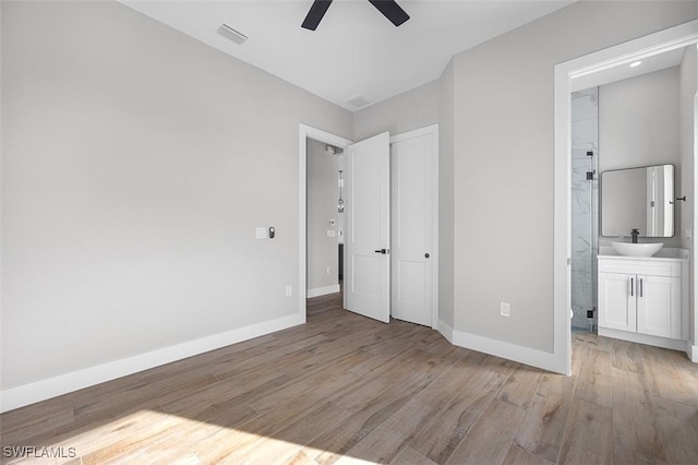 unfurnished bedroom with ceiling fan, light hardwood / wood-style floors, sink, and connected bathroom